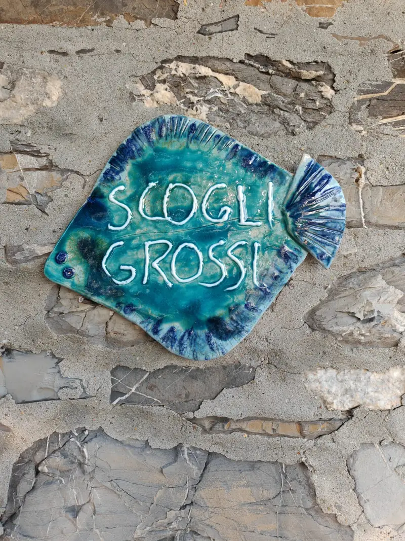 The ceramic Scogli Grossi sign on the stone wall